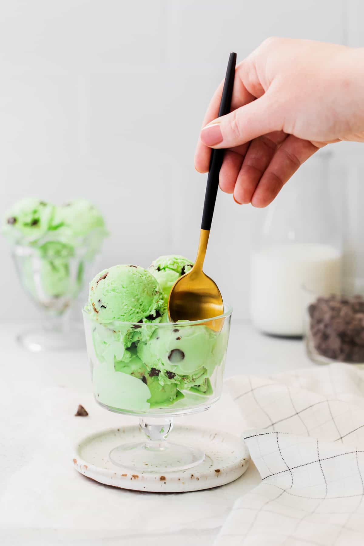 hand digging a spoon into a cup of mint chocolate chip ice cream