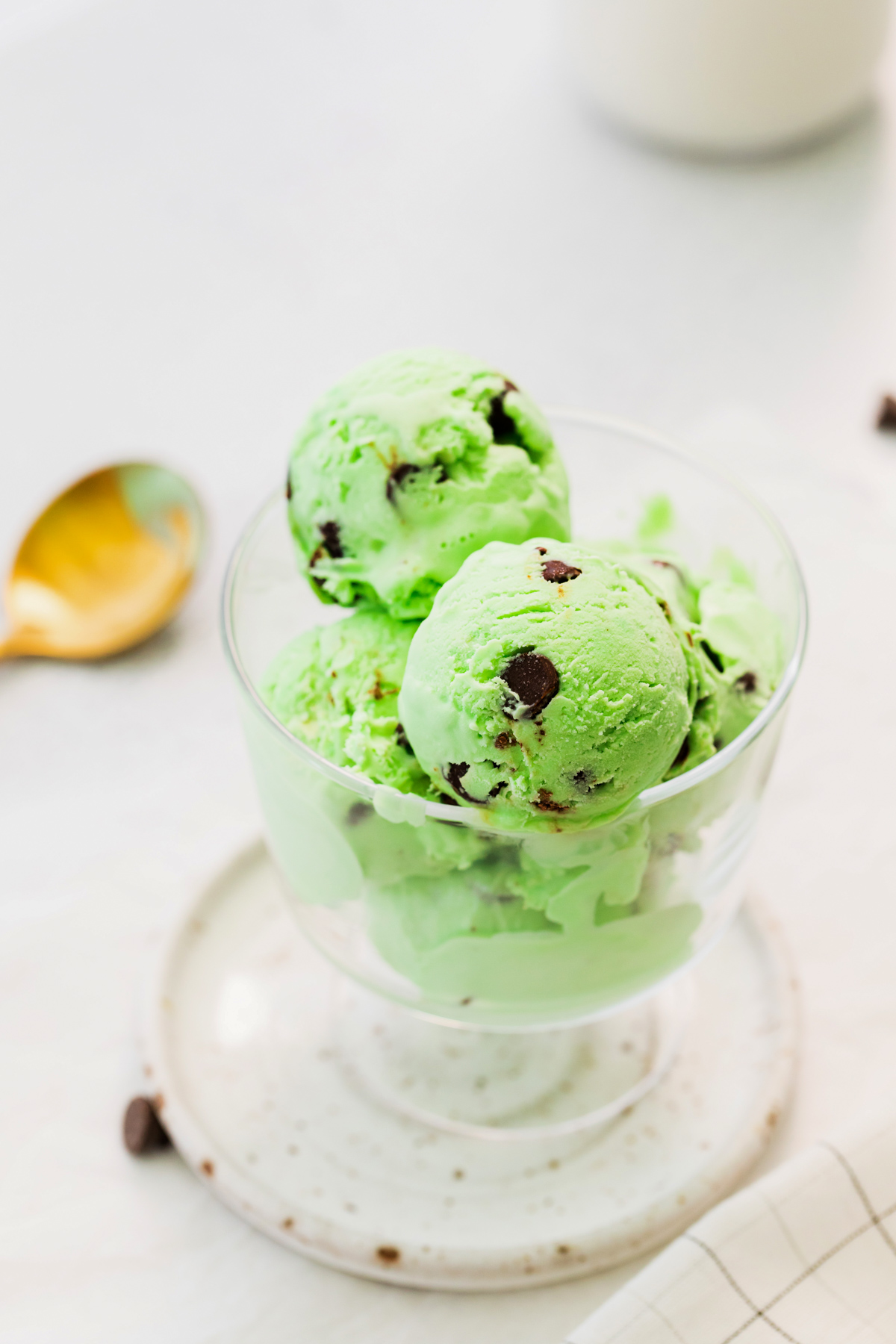 scoops of mint chocolate chip ice cream in a glass dessert bowl