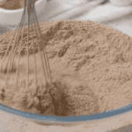 whisking dry ingredients for chocolate cake in a glass bowl.