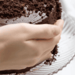 pressing chocolate cake crumbs onto a frosted cake.