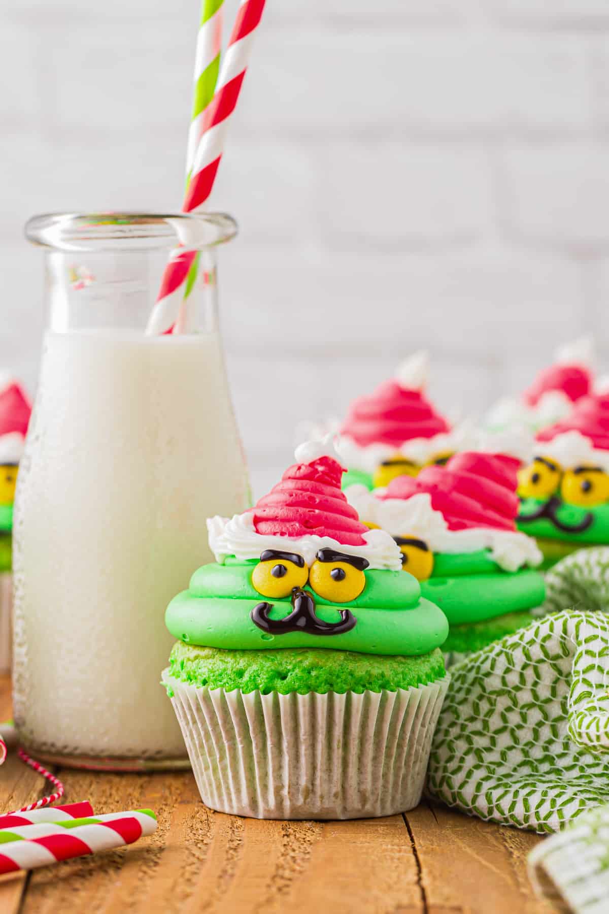grinch cupcakes on a table with a glass of milk
