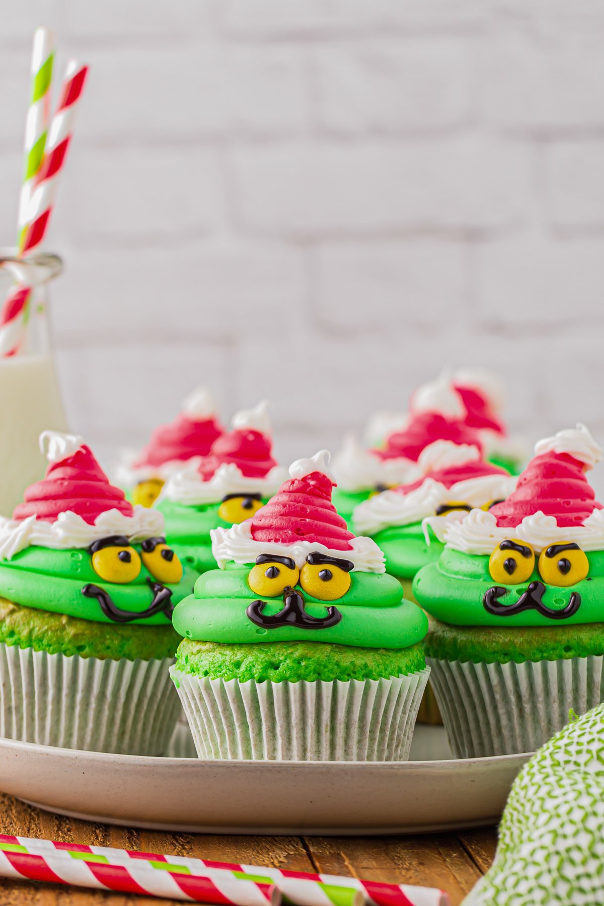 a plate of green cupcakes, decorated like the grinch