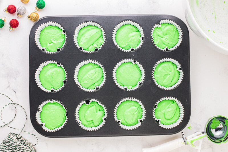 cupcake tin filled with green cupcake batter