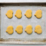pumpkin shaped sugar cookies lined up on a baking tray