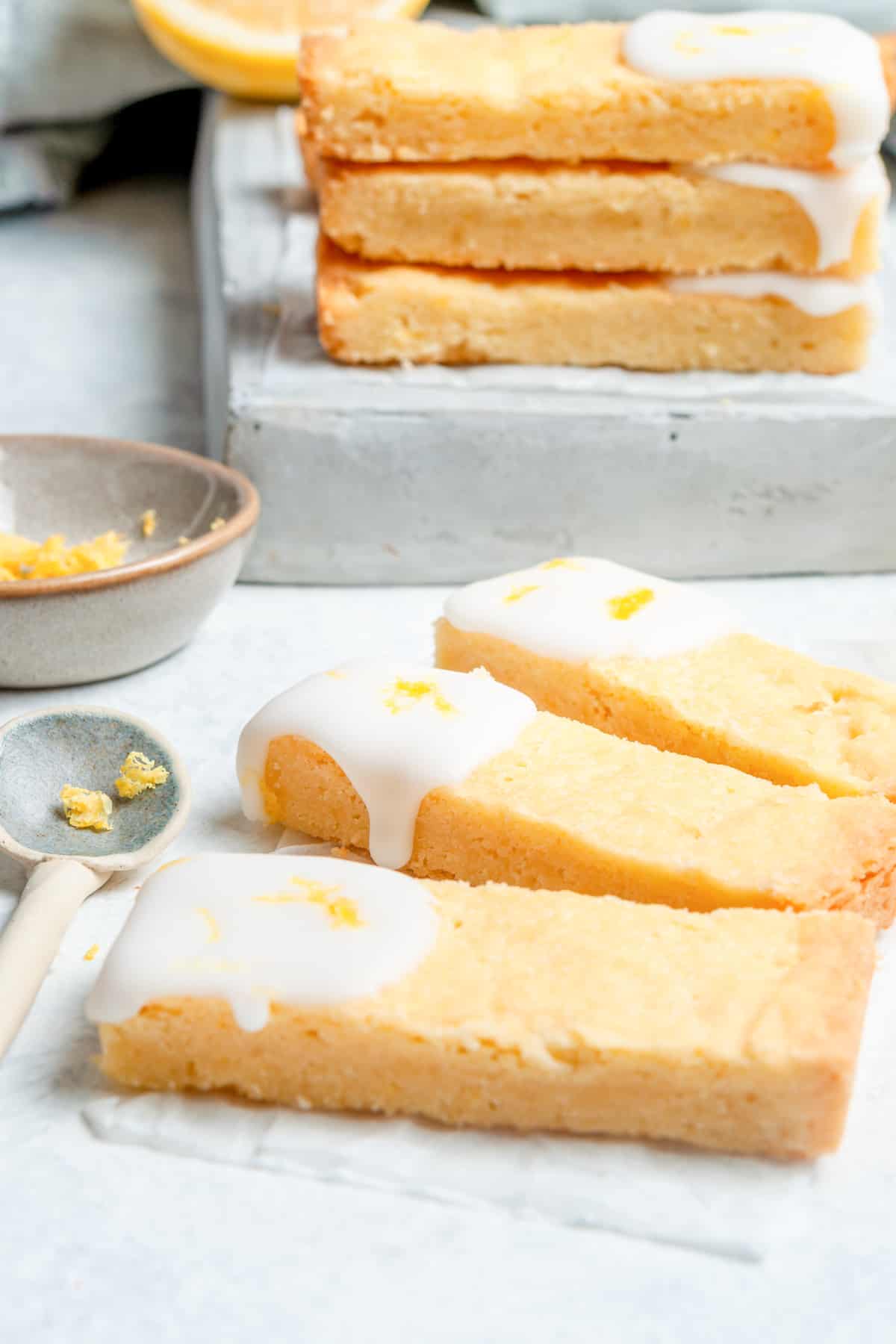 lemon shortbread cookies cut into thin rectangles, with icing drizzled on the ends