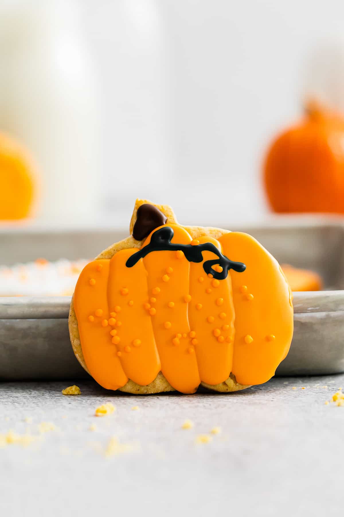 a sugar cookie decorated like a pumpkin with orange frosting