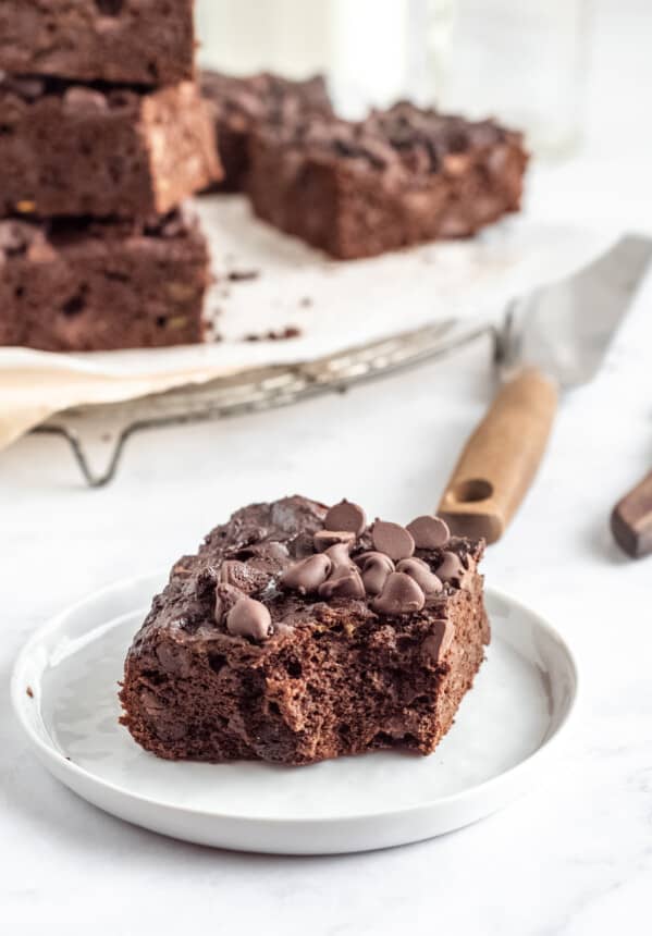 three-quarters view of a bitten avocado brownie on a white plate.