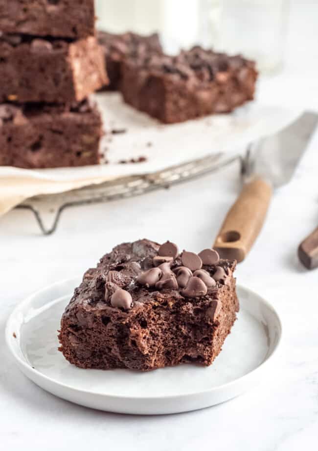 three-quarters view of a bitten avocado brownie on a white plate.