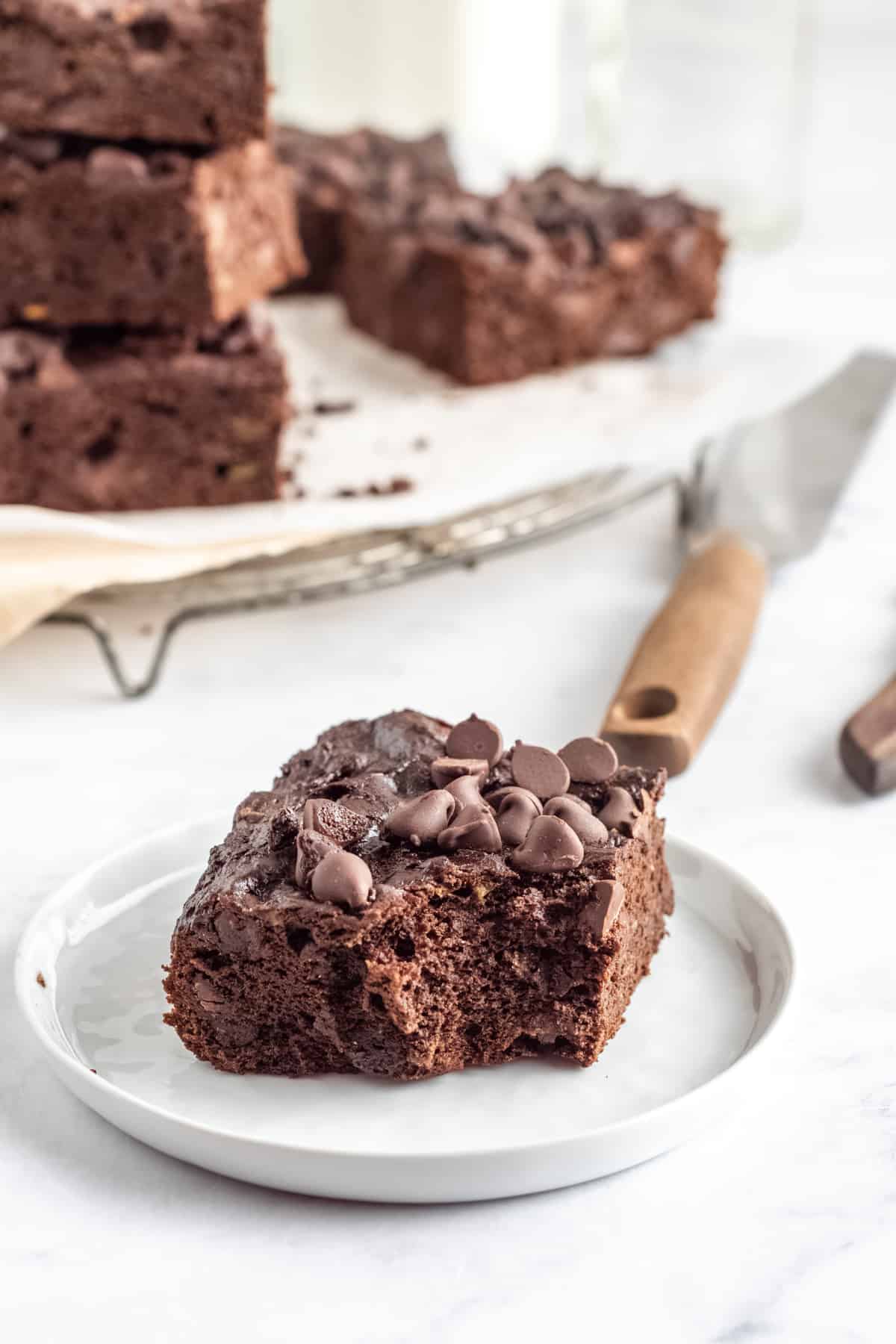 three-quarters view of a bitten avocado brownie on a white plate.