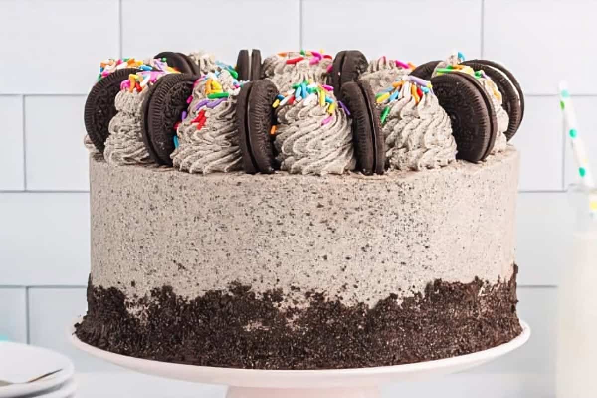 Side view of a frosted chocolate oreo cake on a cake stand.