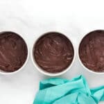 chocolate cake batter divided between three round cake pans.