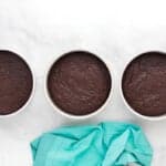 three baked chocolate cake layers in round cake pans.