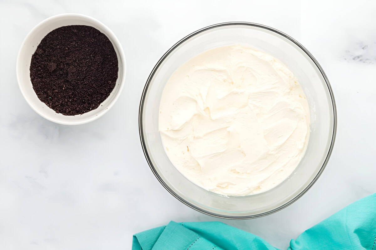 buttercream frosting in a bowl next to a bowl of crushed oreos.