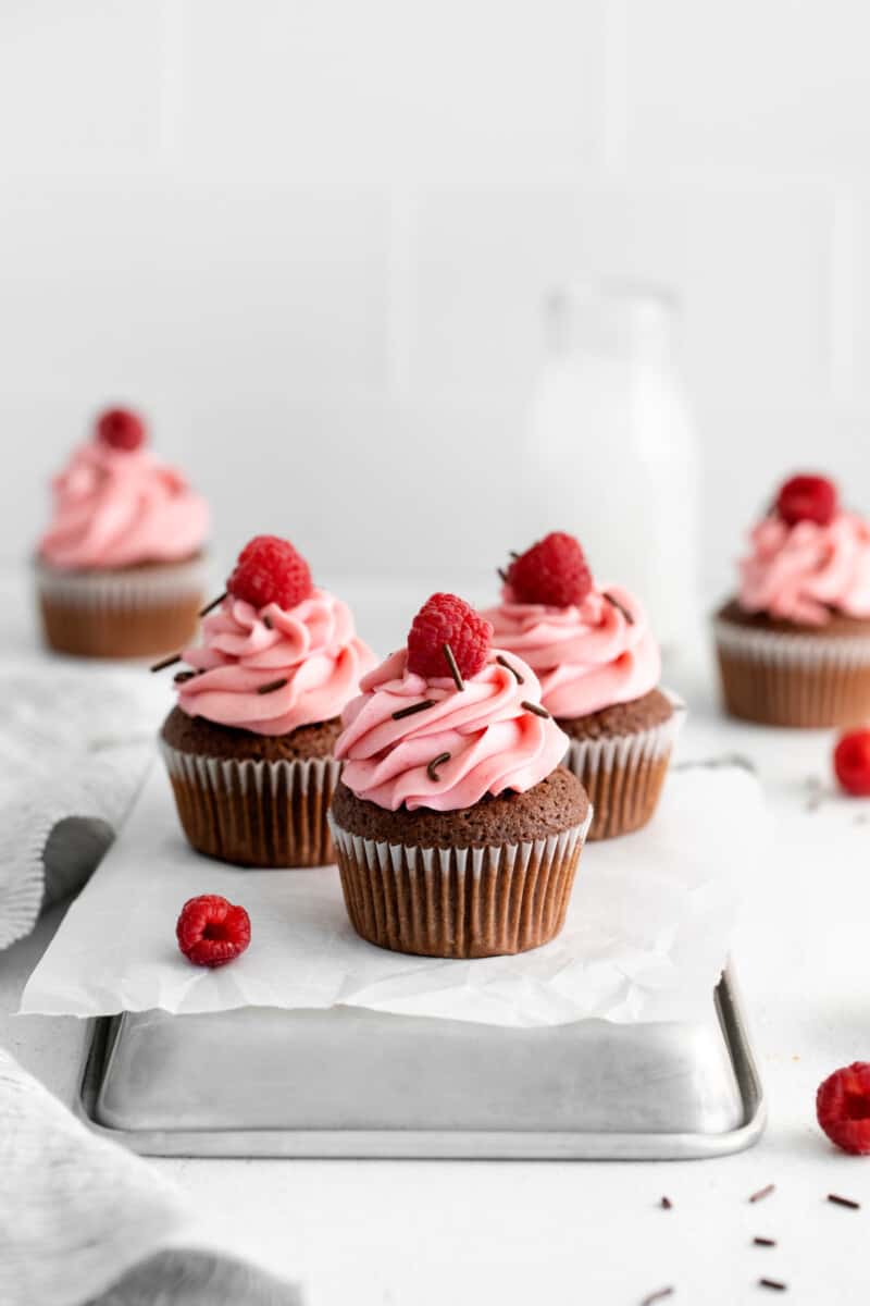 3 chocolate raspberry cupcakes on an overturned square cake pan.