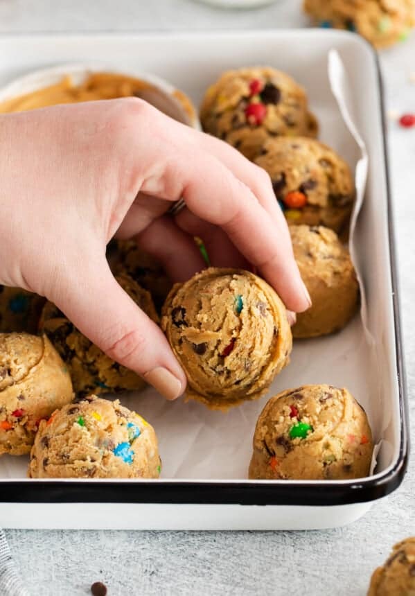 A hand grabbing a cookie from a baking sheet.