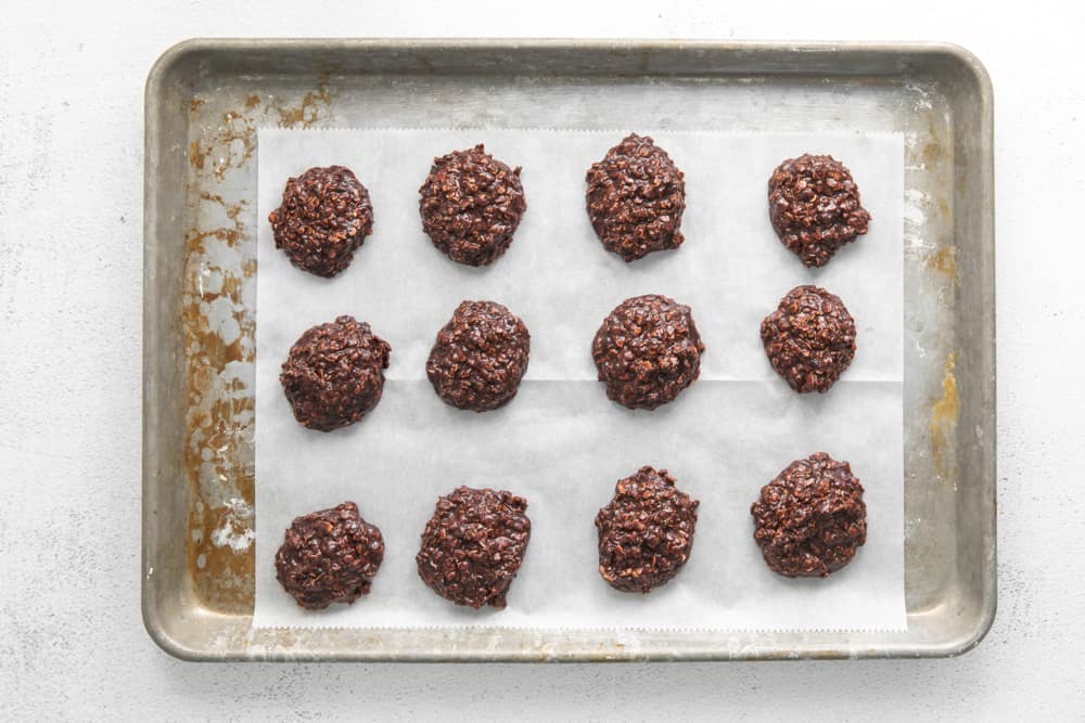 no bake cookies lined up on a baking tray covered with parchment paper