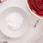 a bowl of red frosting and a bowl of flour.