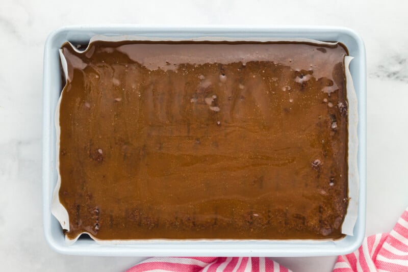 caramel poured over brownies in a rectangular baking pan.