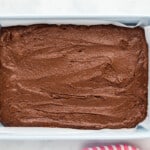 chocolate brownie batter spread out in a rectangular baking pan.