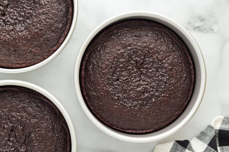 3 baked chocolate fudge cake layers in round cake pans.