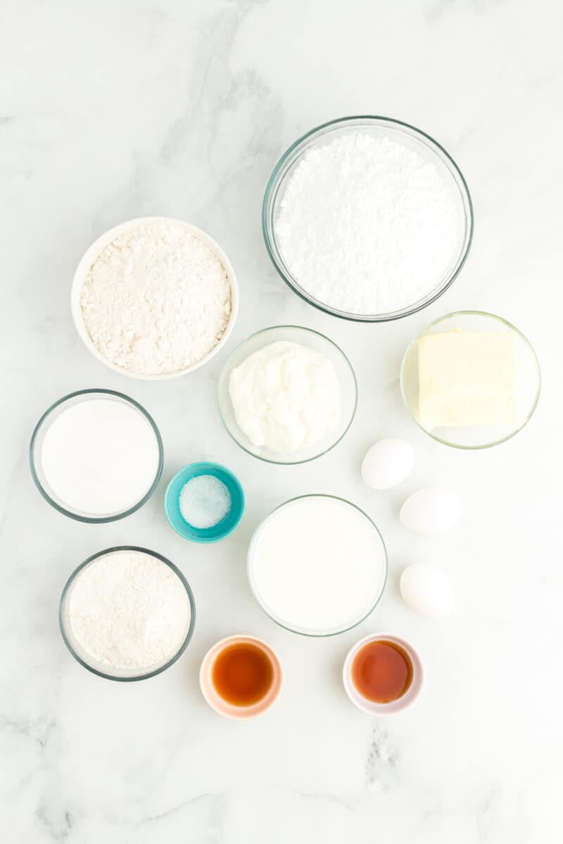 overhead view of ingredients for doctored white cake mix in individual bowls.