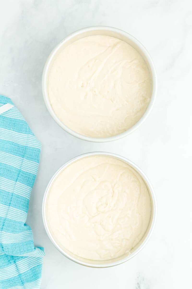 doctored white cake mix batter in round baking pans.