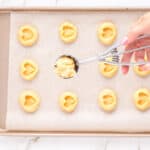 a hand using a cookie scoop to portion cookies onto a baking sheet.