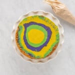 overhead view of king cake cheesecake on a white cake stand.