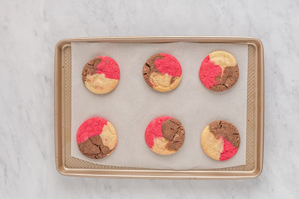 a tray of cookies with red and pink icing on it.