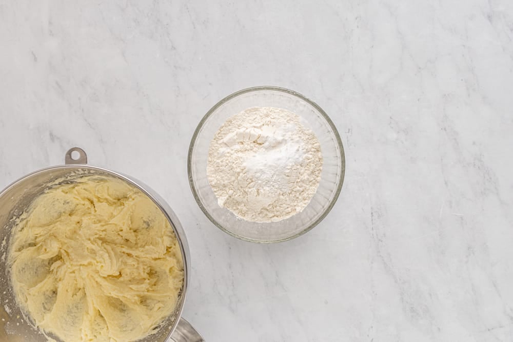 a bowl of flour and a bowl of sugar next to each other.