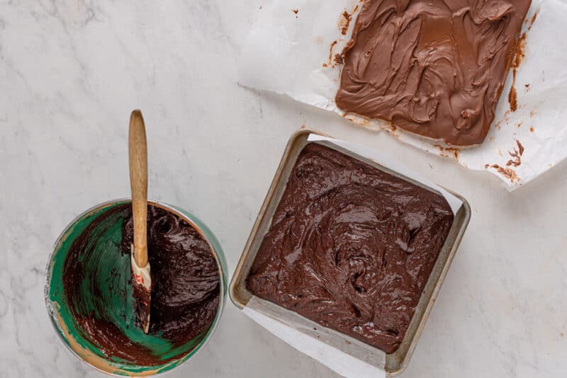 two pans of chocolate fudge on a marble table.