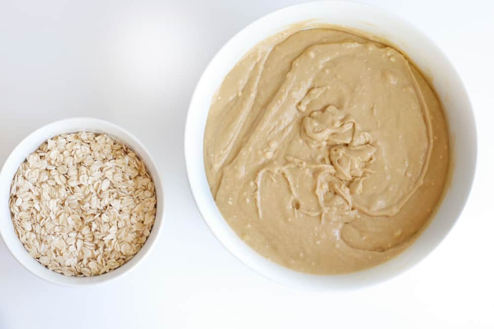 overhead view of a large bowl of cookie batter, next to a small bowl of oats