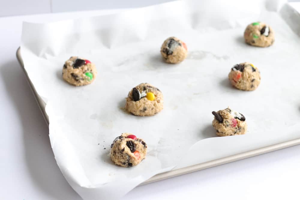 cookie dough balls arranged on a parchment lined baking tray