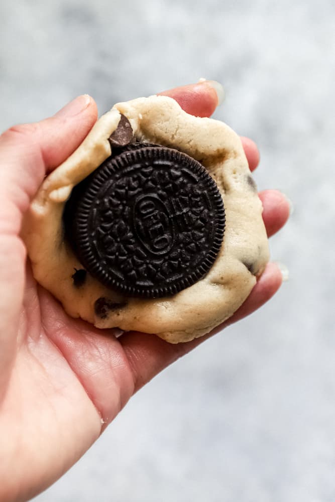 hand holding cookie dough, with an oreo at the center