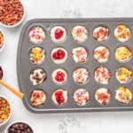 mini muffin tin filled with pancake batter, with a variety of toppings