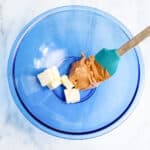 a blue bowl with a spoon and butter.