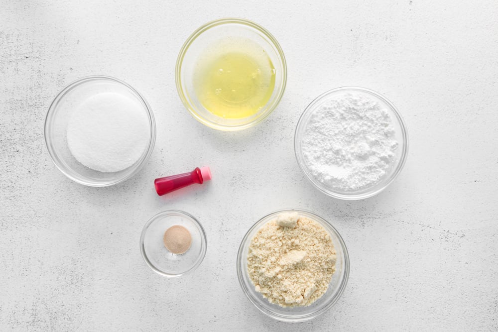 overhead view of ingredients for raspberry macaron shells in individual bowls.