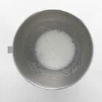 whisked sugar and egg whites in a stainless mixing bowl.