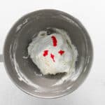 food coloring added to raspberry macaron batter in a stainless mixing bowl.