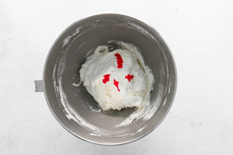 food coloring added to raspberry macaron batter in a stainless mixing bowl.