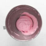 colored raspberry macaron shell batter in a stainless mixing bowl.