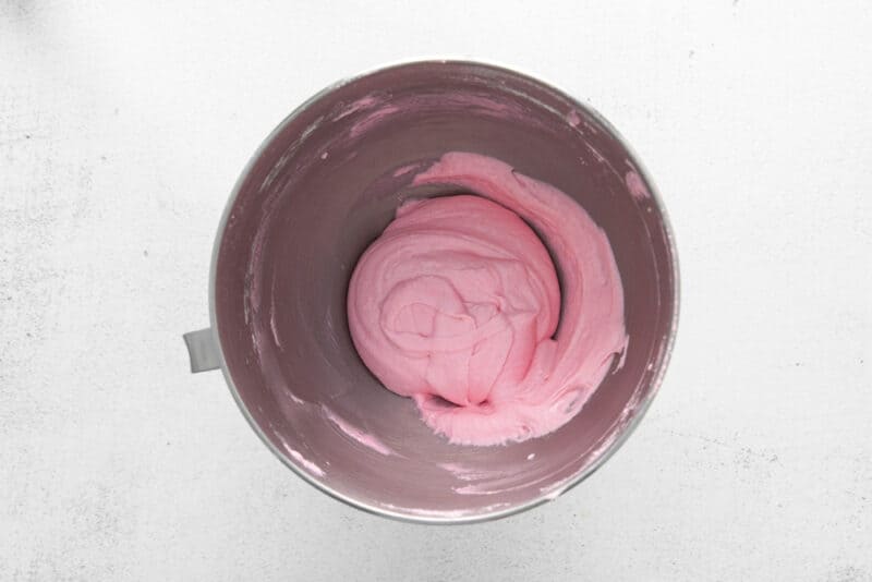 colored raspberry macaron shell batter in a stainless mixing bowl.