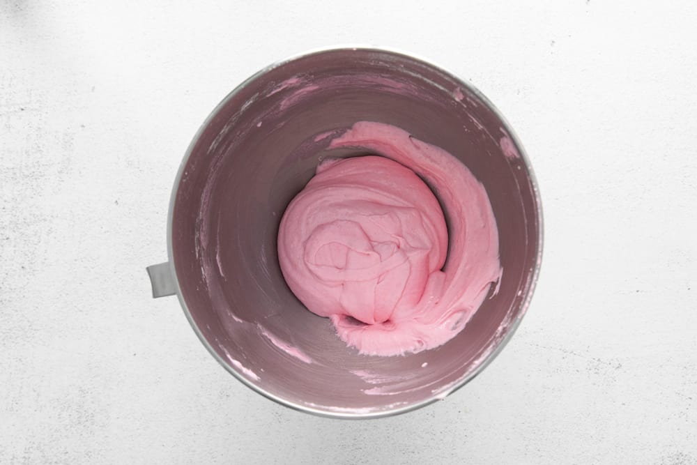 pink meringue batter in a stainless steel bowl.
