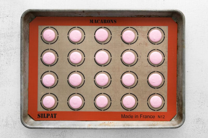 piped raspberry macaron batter on a silpat lined baking sheet.