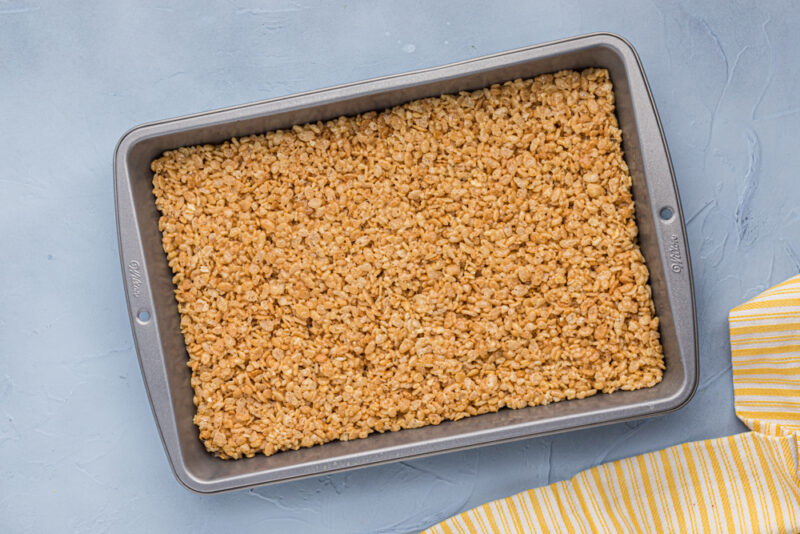 a baking pan filled with granola on a blue background.