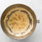 top view of a metal mixing bowl with a yellow batter in it.