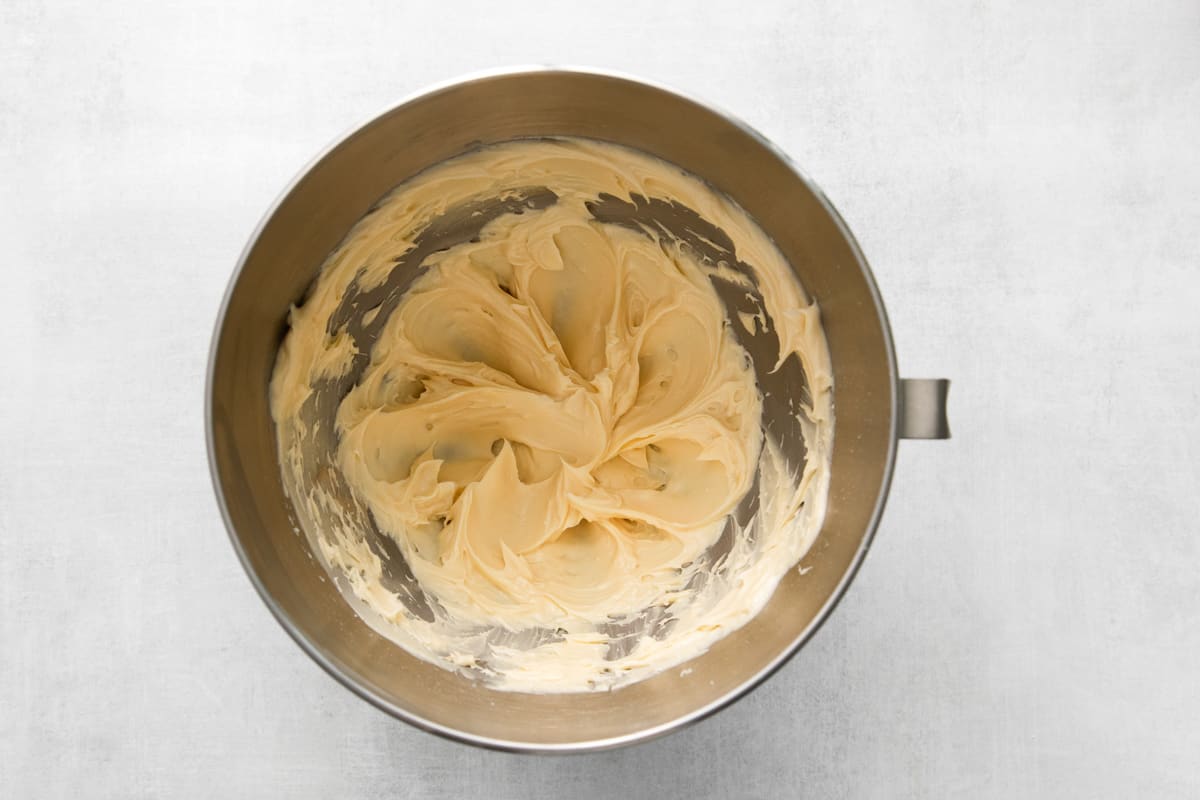 top view of a metal mixing bowl with a yellow batter in it.