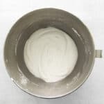 whipped cream in a metal bowl on a white background.