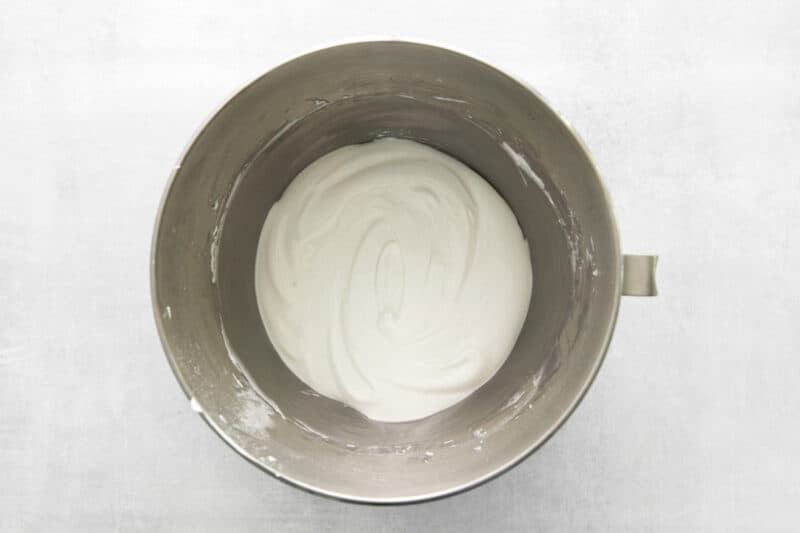whipped cream in a metal bowl on a white background.