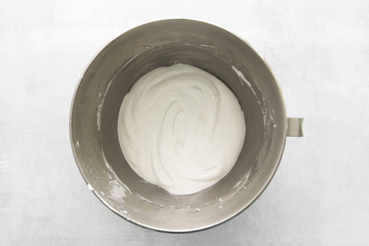 whipped cream in a metal bowl on a white background.